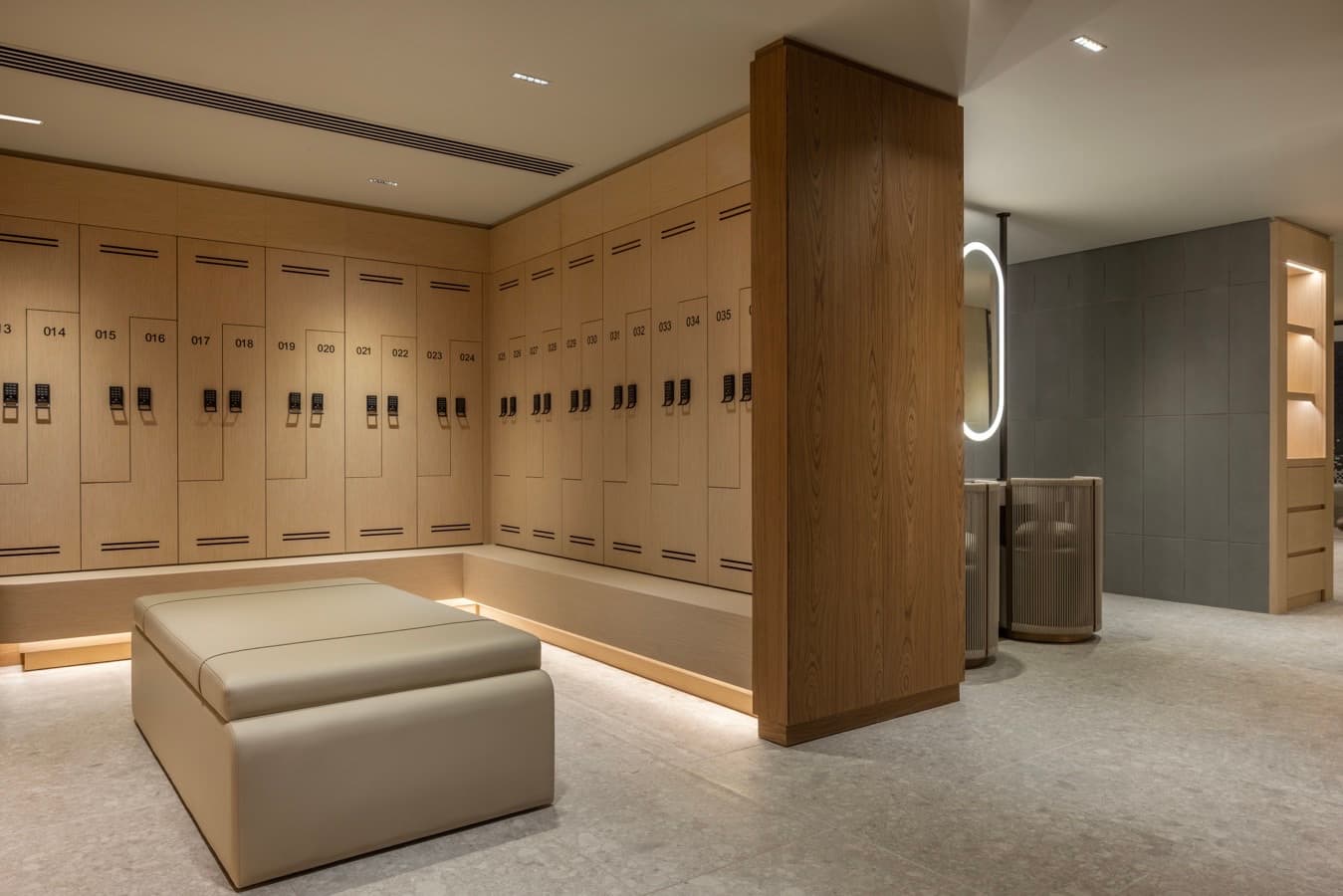 Locker room corner with a backlit vanity mirror beyond