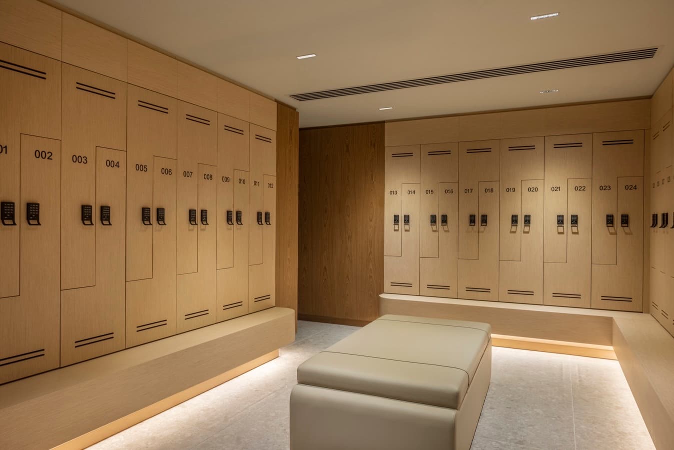 Changing room with pale-oak lockers, keypad locks and a leather bench