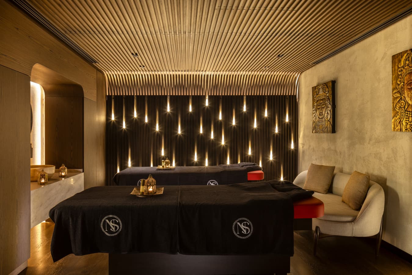 Couples suite with twin massage beds, a lounge sofa and a gilded artwork on suede-finished walls