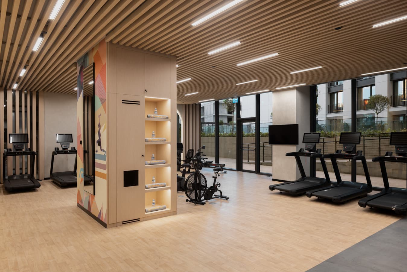 Cardio zone with treadmills and exercise bikes beside floor-to-ceiling windows