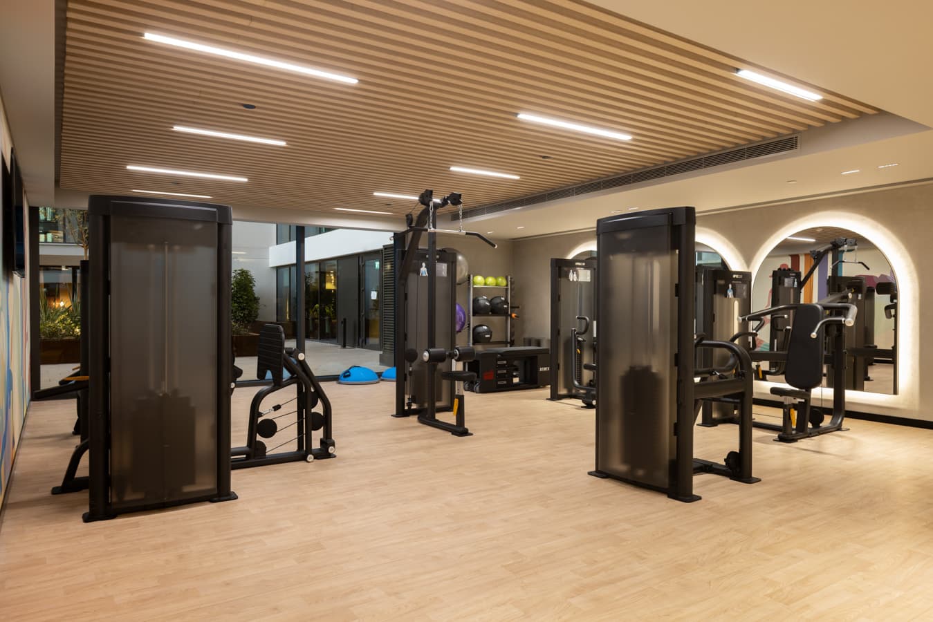 Strength training area with cable machines framed by illuminated arches