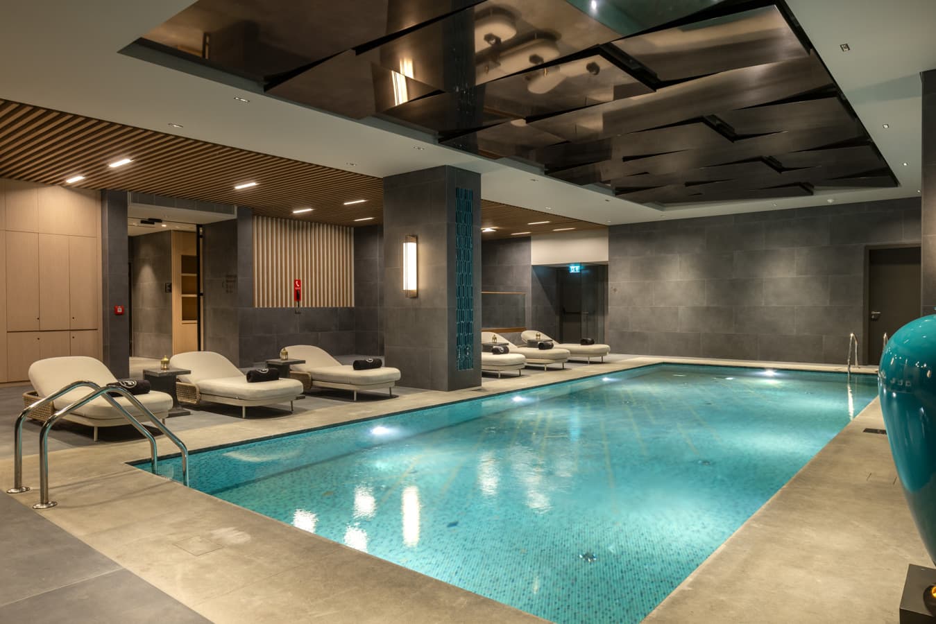 Indoor pool in the evening with loungers along the edge and a mirrored ceiling