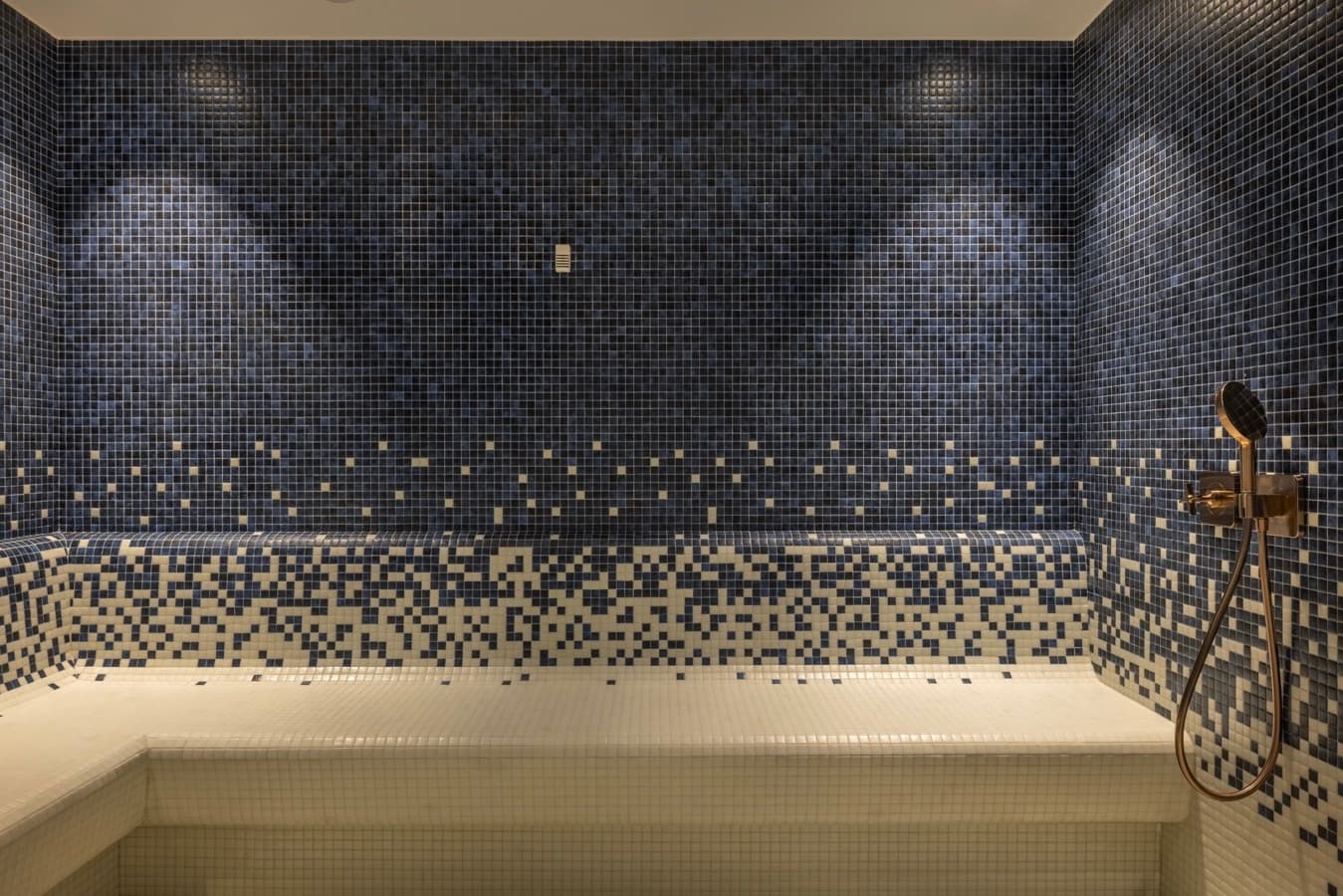 Blue mosaic steam room with a bronze hand shower