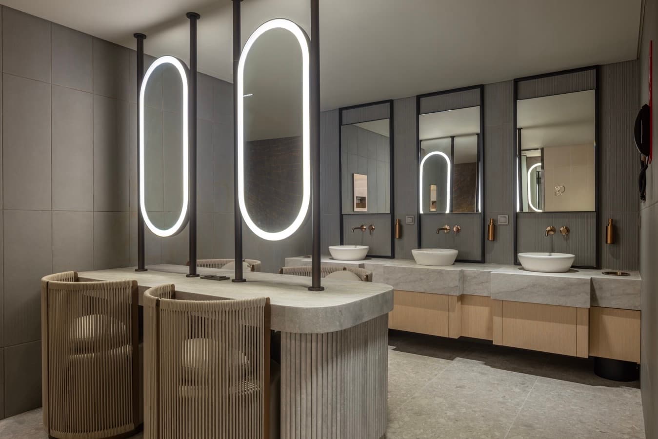 Dressing area with oval mirrors, stone counter and oak shelving