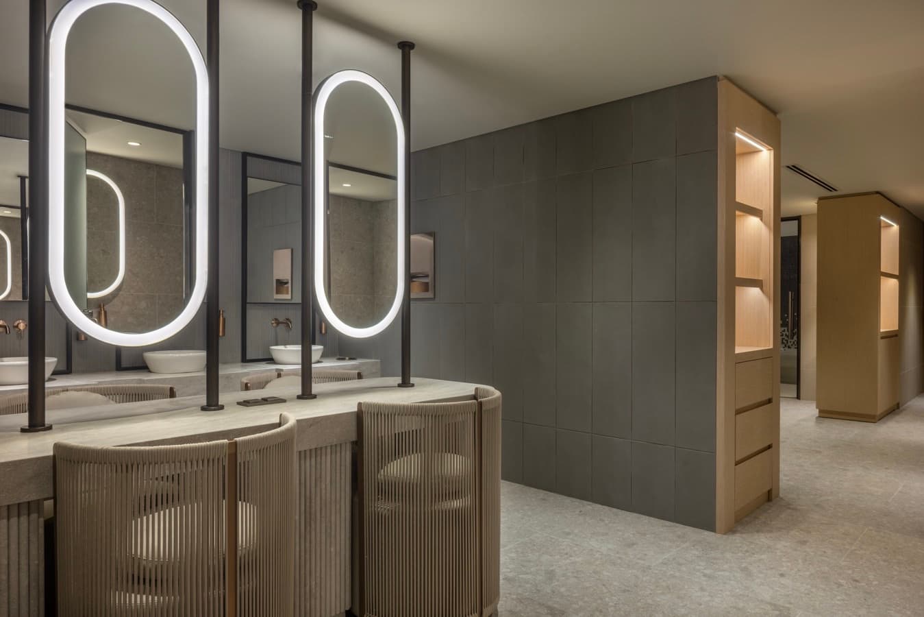 Vanity counter with backlit oval mirrors, stone basins and bronze taps