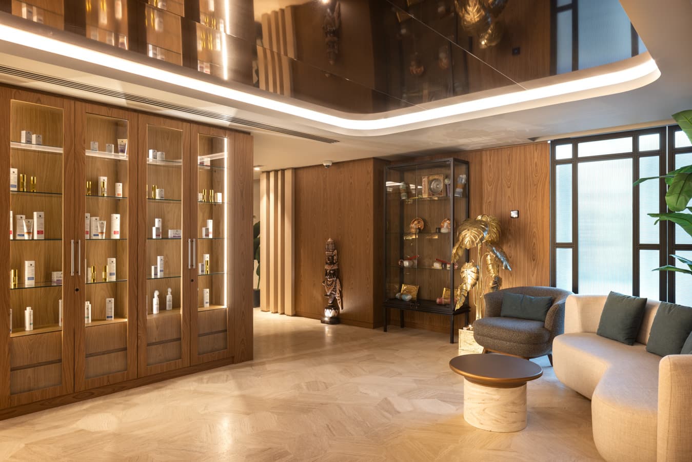 Boutique corner with illuminated product cabinets, a bronze figure and lounge seating by the windows