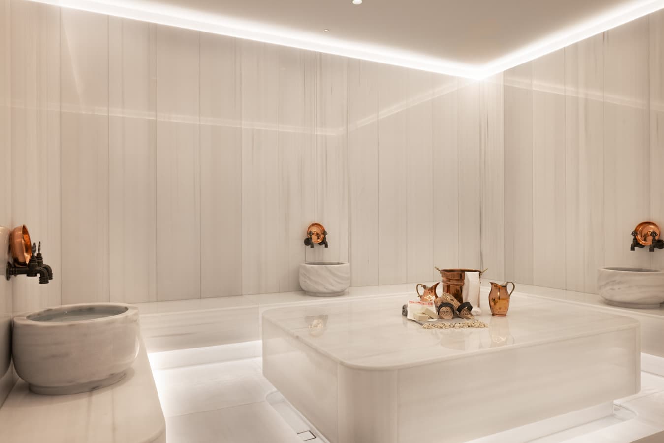 Turkish hammam with heated white marble navel stone, marble basins and copper taps at Navitas Spa Hilton Istanbul Airport